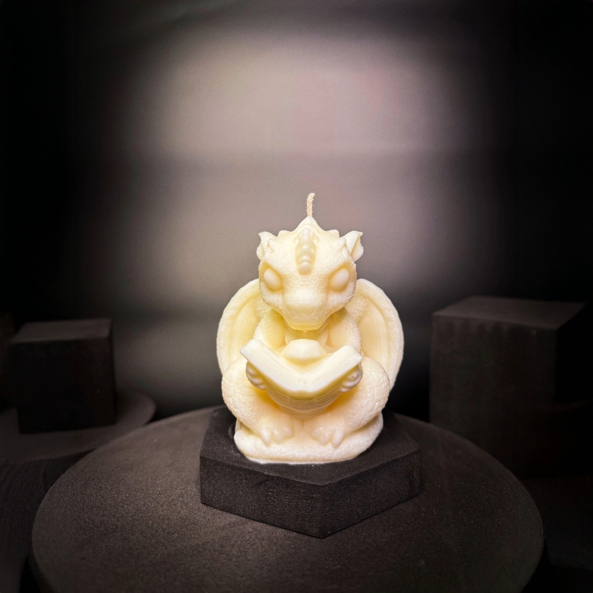 Handmade soy wax dragon candle reading a book, fantasy themed home decor piece from a Norwegian studio.