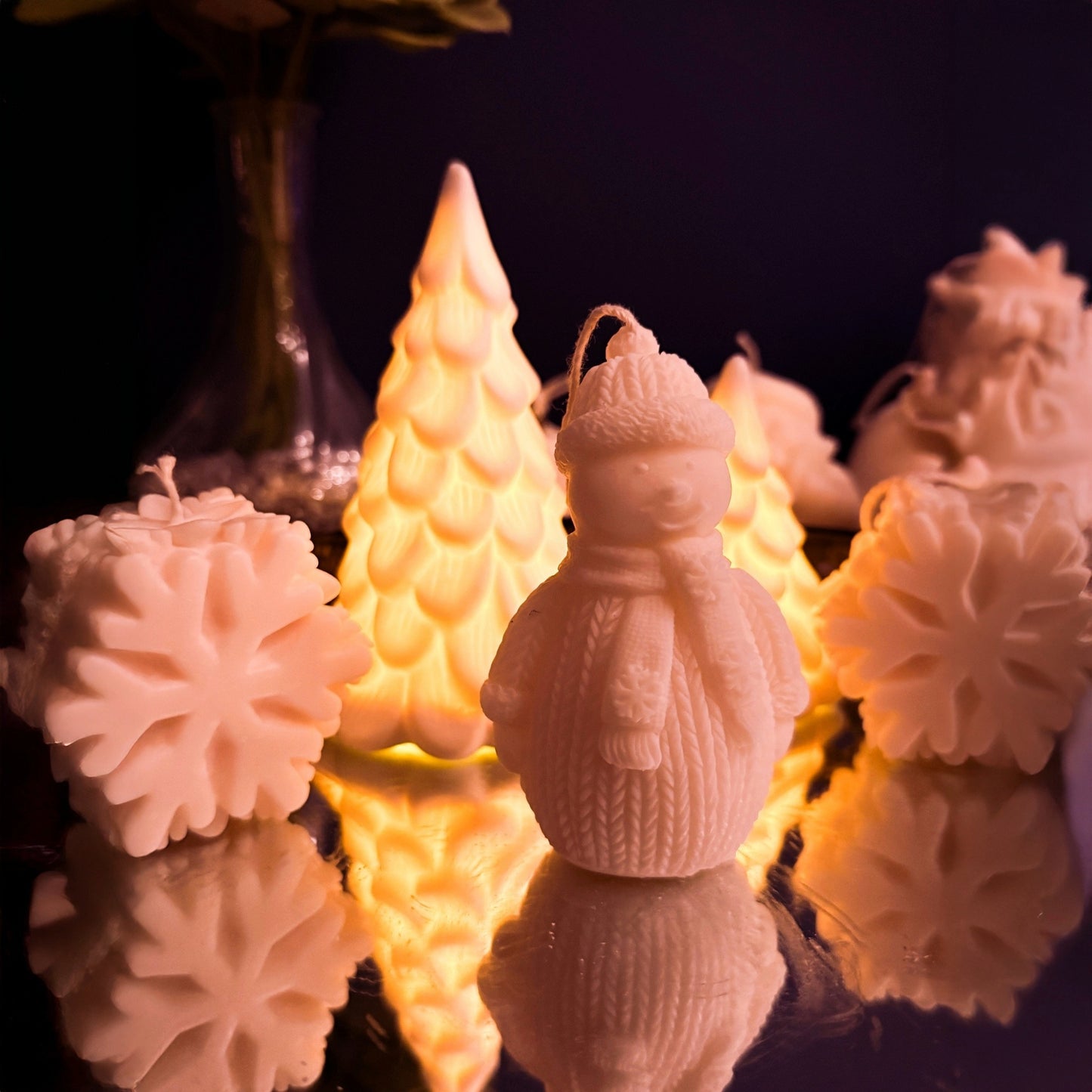 Artisan snowman-shaped soy wax candle viewed from the left, detailed knitted winter clothing design, festive decorative candle for holiday styling.