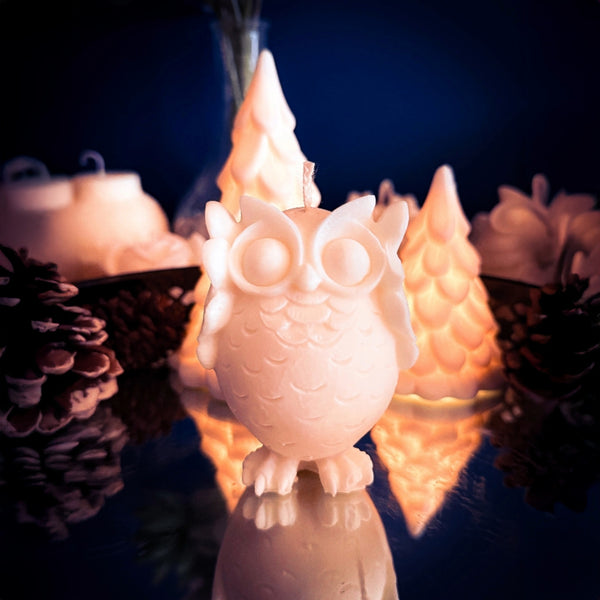 The Playful Owl handmade soy wax candle styled with pinecones and winter decor.