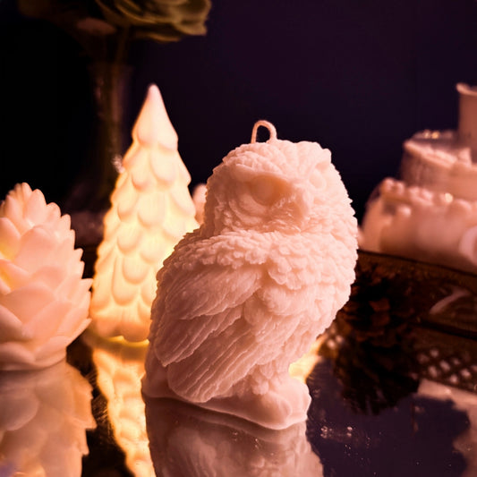 White soy wax snowy owl candle photographed from the side, highlighting layered feather texture and winter decor styling.