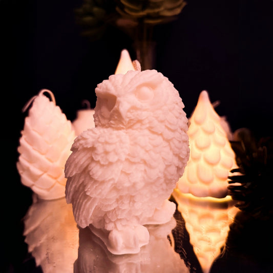 Close-up of handcrafted snowy owl candle in soy wax showing detailed feathers and winter inspired design.
